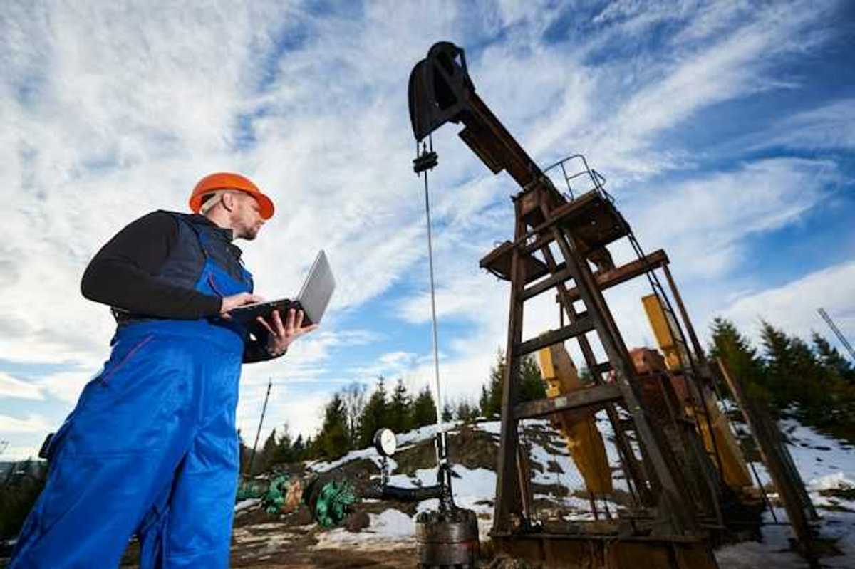 A worker inspecting an oil well in a snowy location