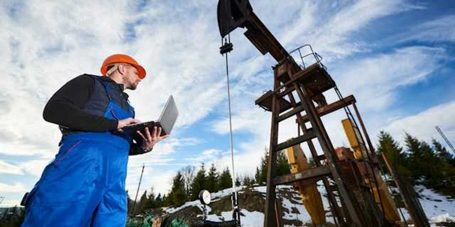 A worker inspecting an oil well in a snowy location