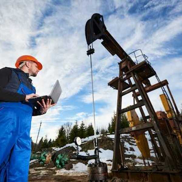 A worker inspecting an oil well in a snowy location