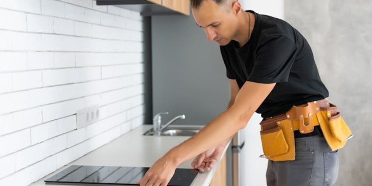 A worker installing an induction cooktop on a kitchen counter