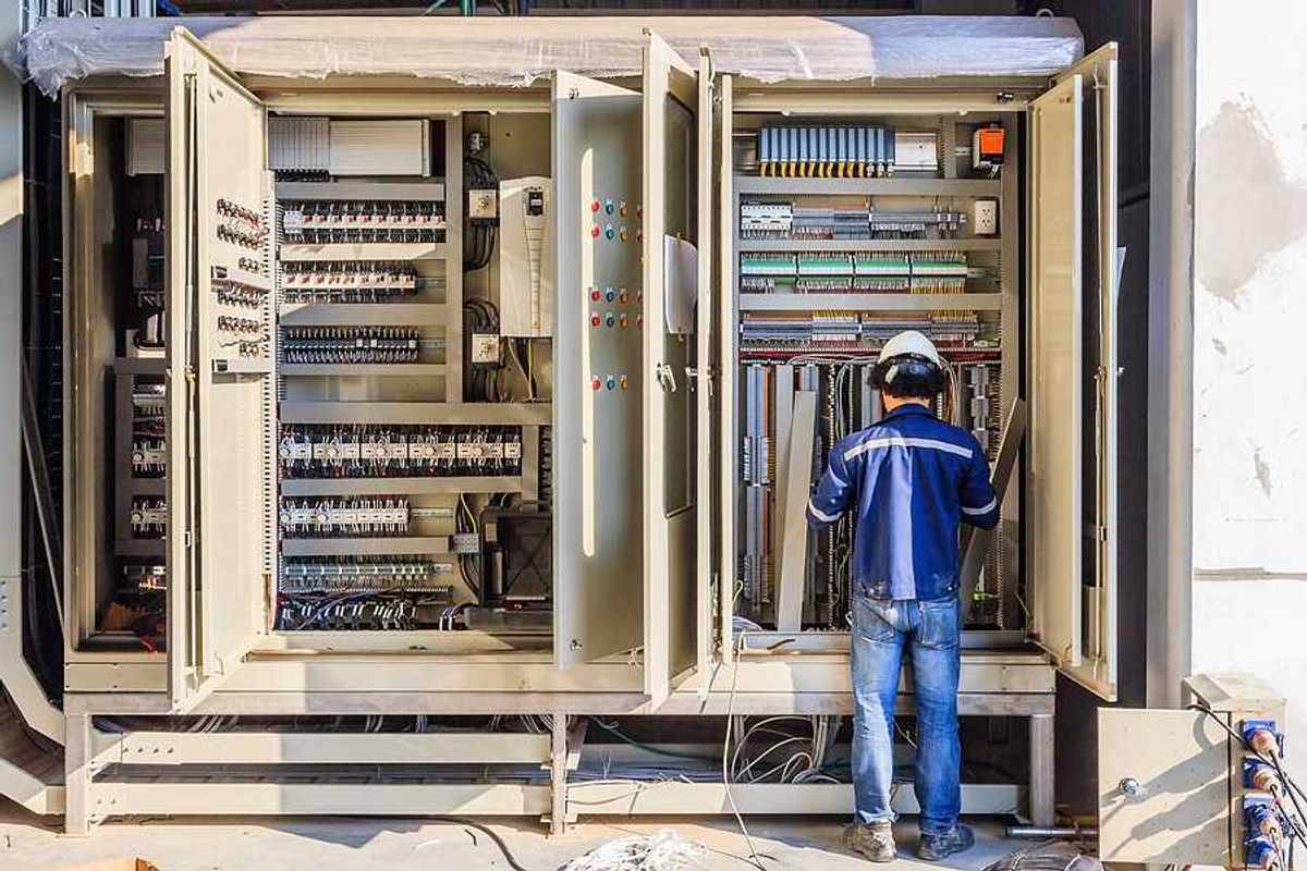 A worker installing electronics in a large industrial cabinet