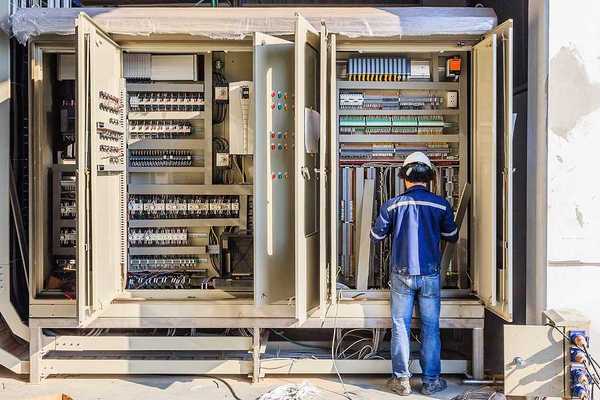 A worker installing electronics in a large industrial cabinet
