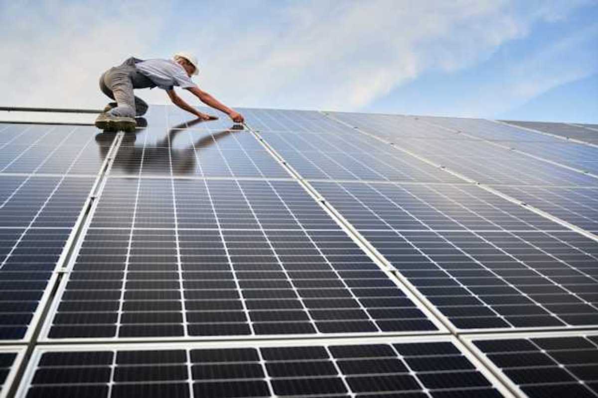 A worker installing solar panels on a roof