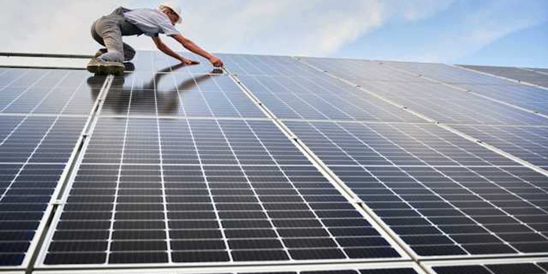 A worker installing solar panels on a roof