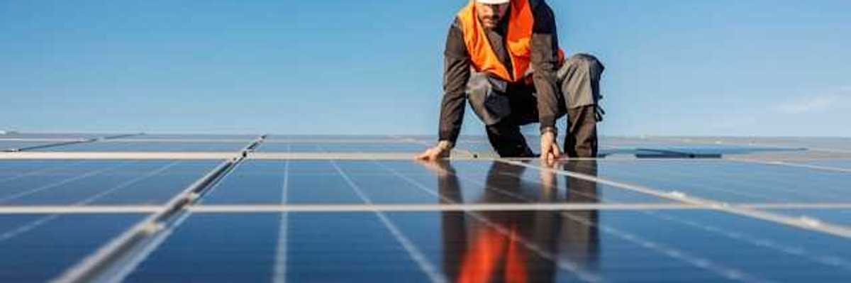 A worker installing solar panels on a roof