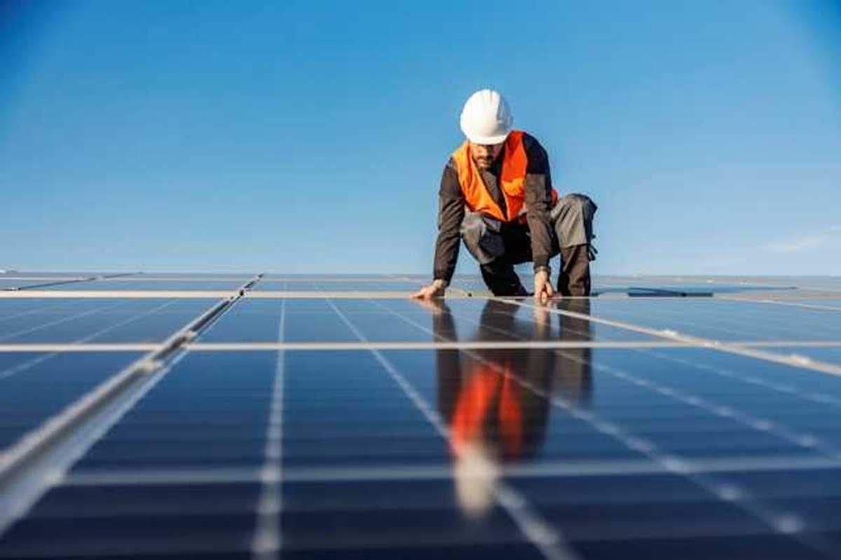 A worker installing solar panels on a roof