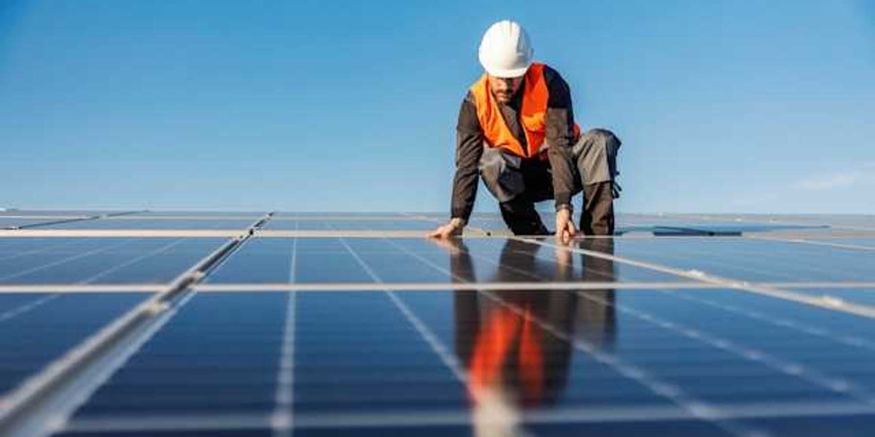 A worker installing solar panels on a roof