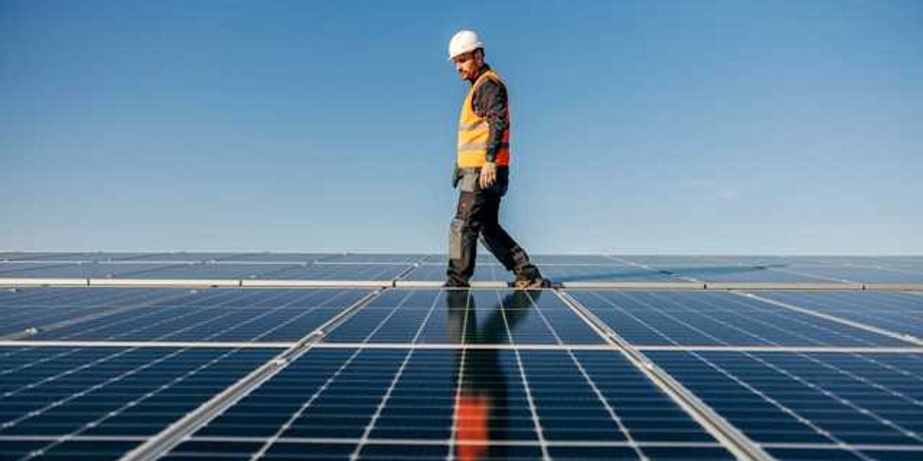 A worker walking among solar panels
