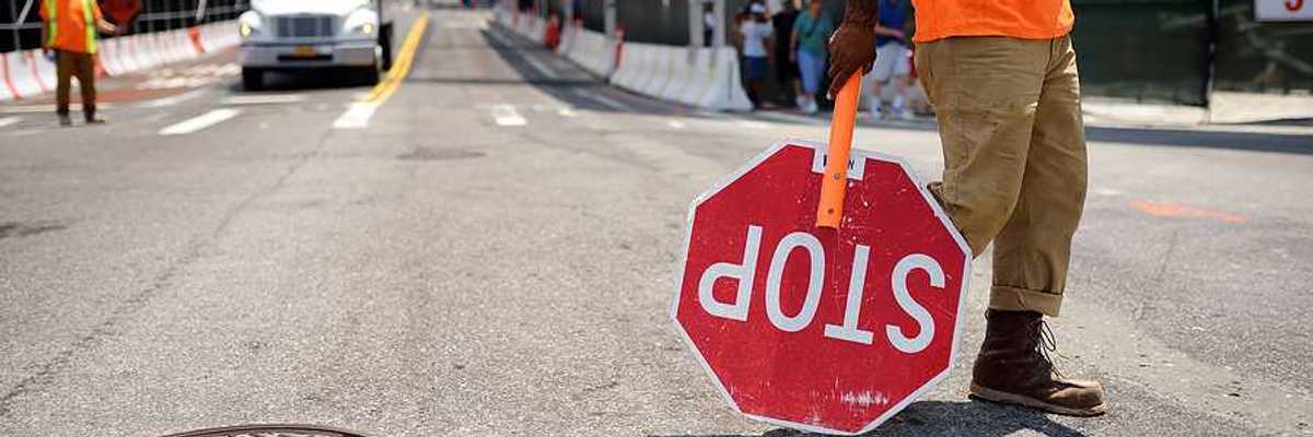 A worker with a stop sign directing traffic in a construction zone