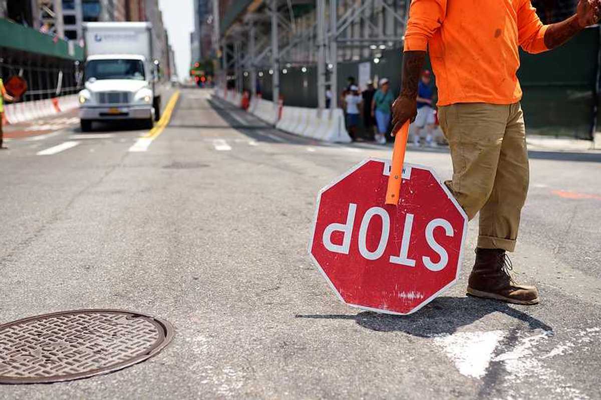 A worker with a stop sign directing traffic in a construction zone