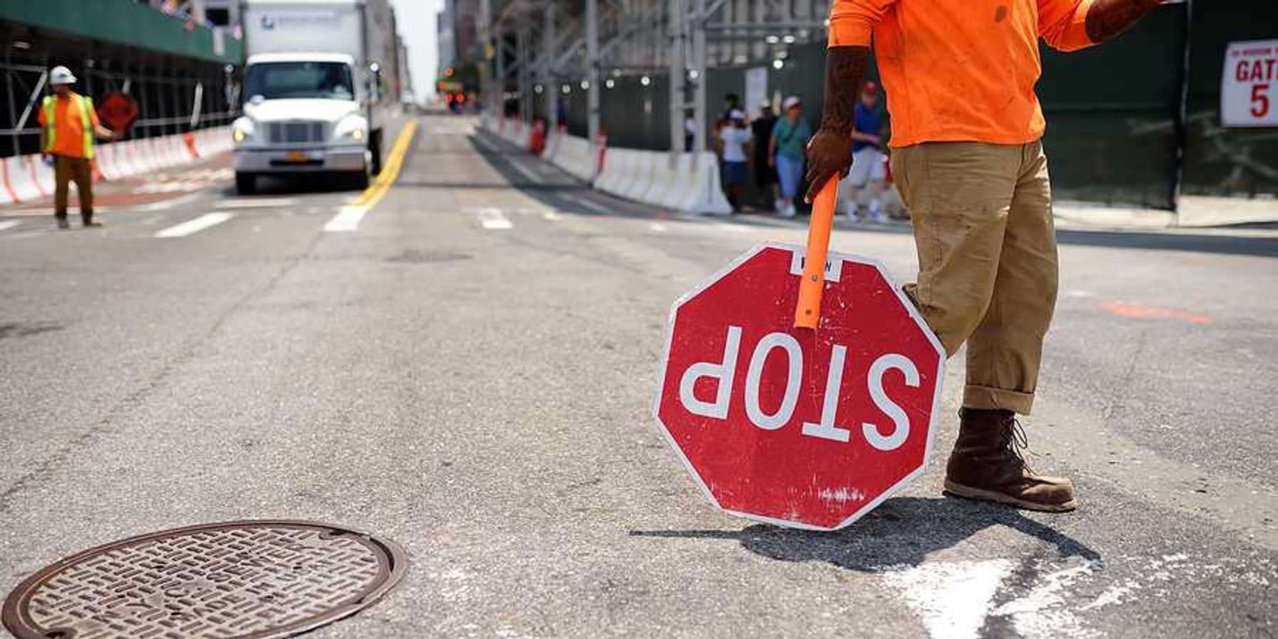 A worker with a stop sign directing traffic in a construction zone