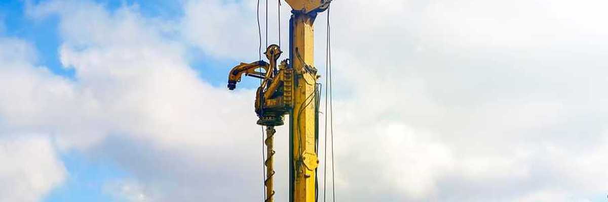 A yellow drilling tower against a cloudy sky