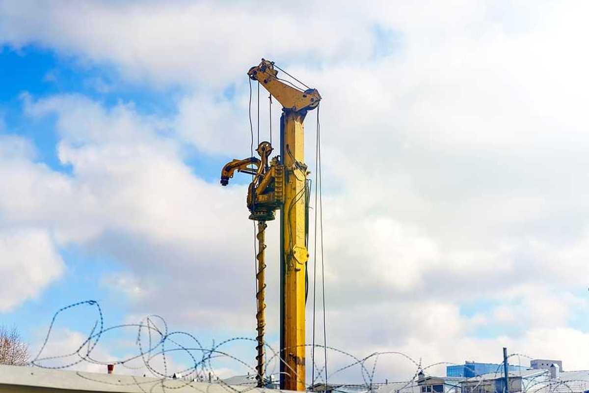 A yellow drilling tower against a cloudy sky