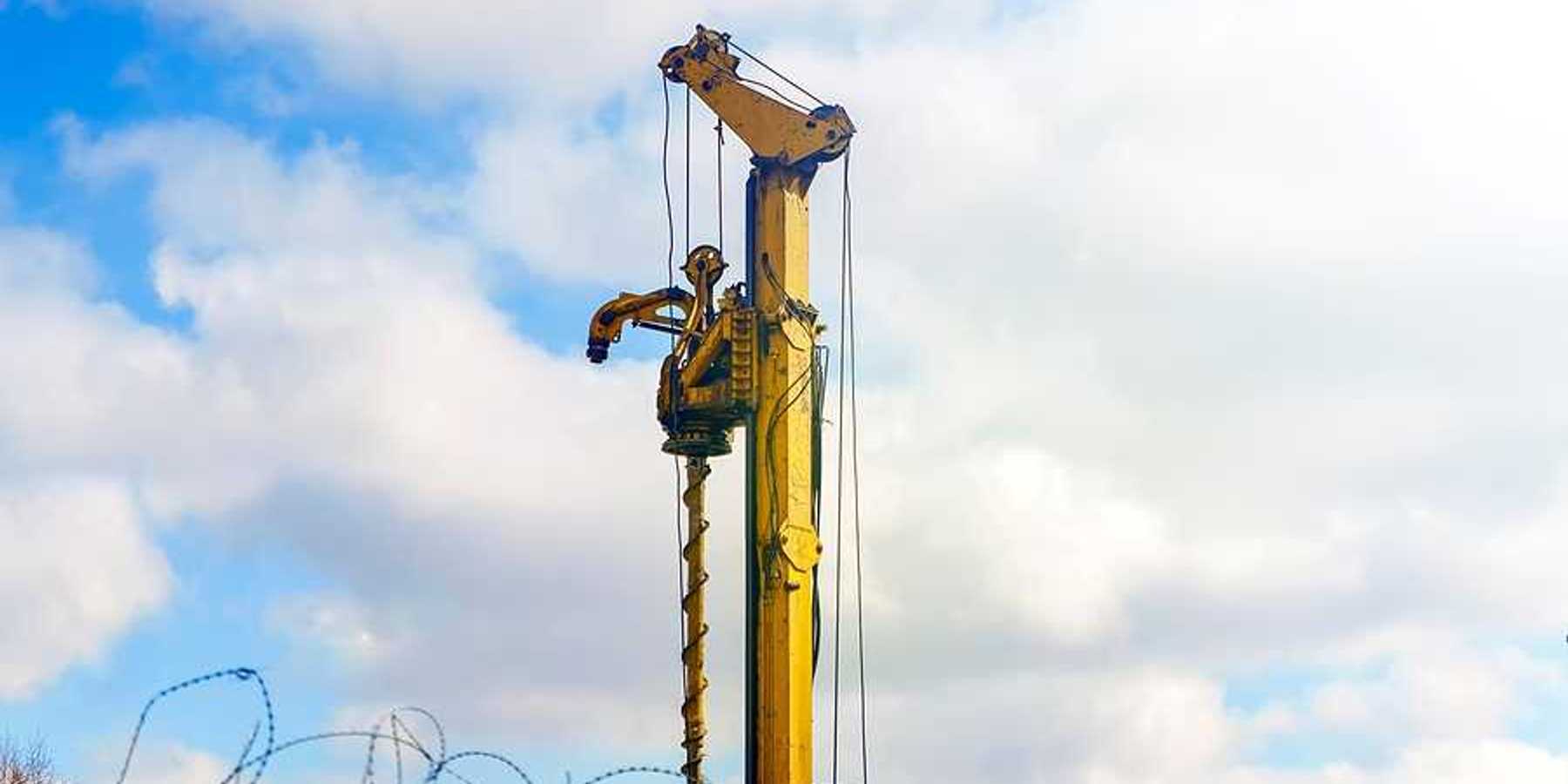 A yellow drilling tower against a cloudy sky