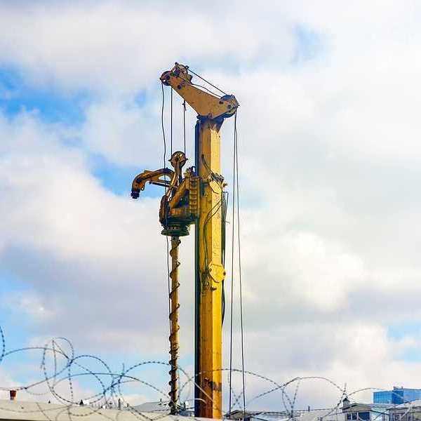 A yellow drilling tower against a cloudy sky