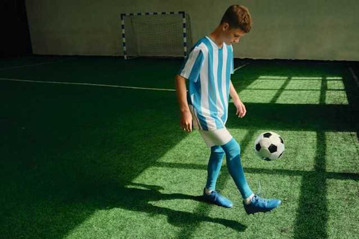 A young boy kicking a soccer ball on an artificial turf surface