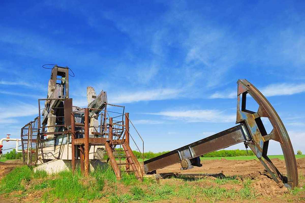 Abandoned oil pump jack in field summer day