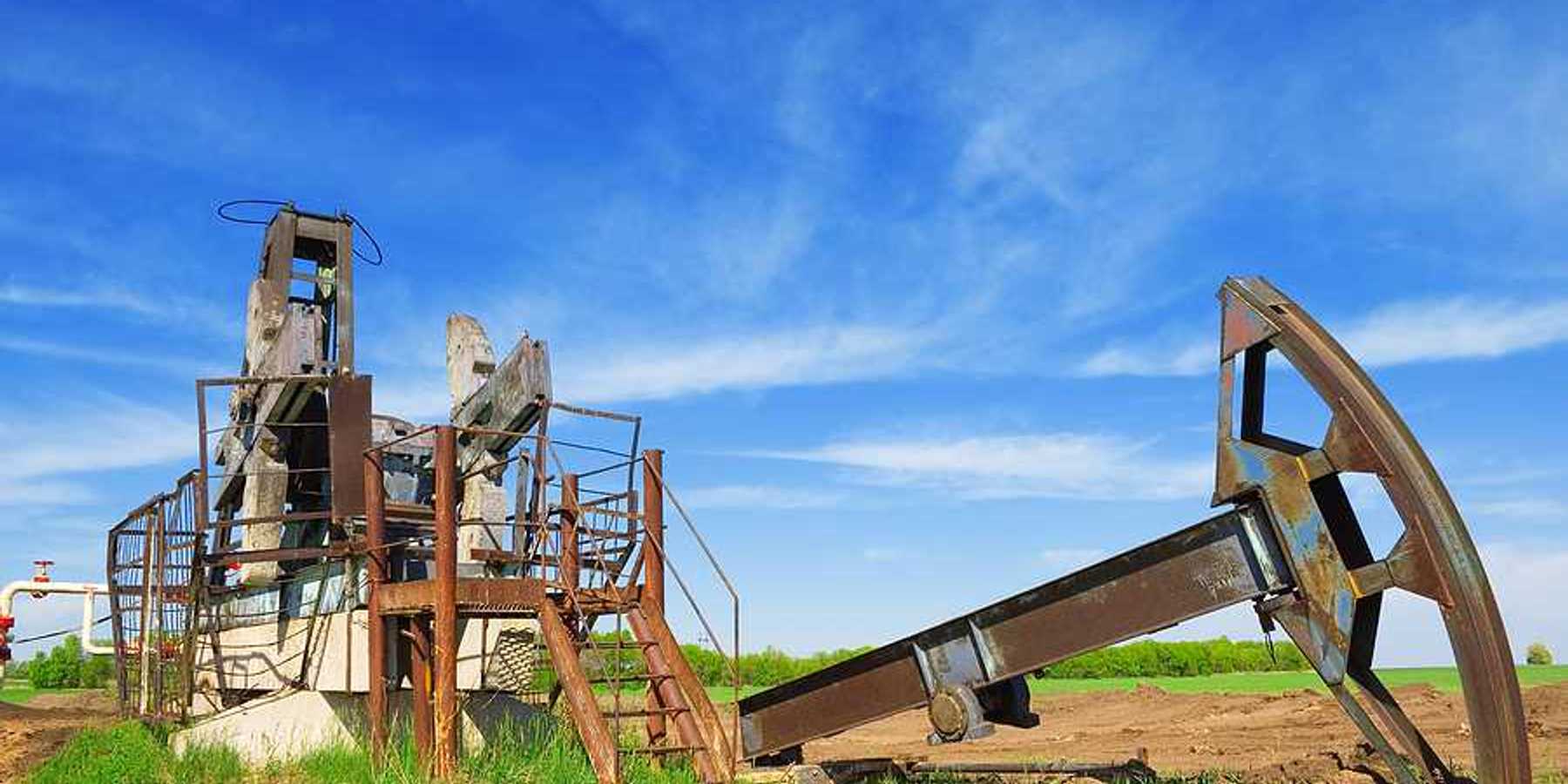 Abandoned oil pump jack in field summer day