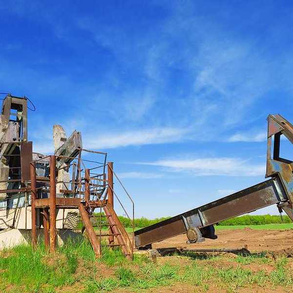 Abandoned oil pump jack in field summer day
