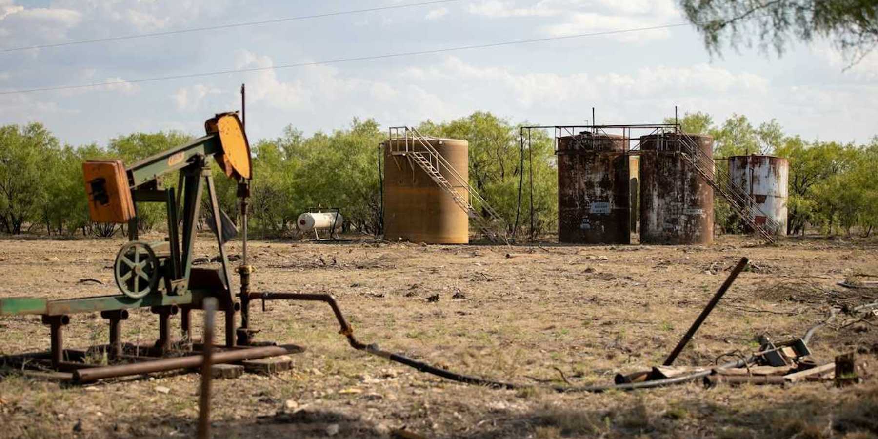 Abandoned oil well adjacent to rusting storage tanks