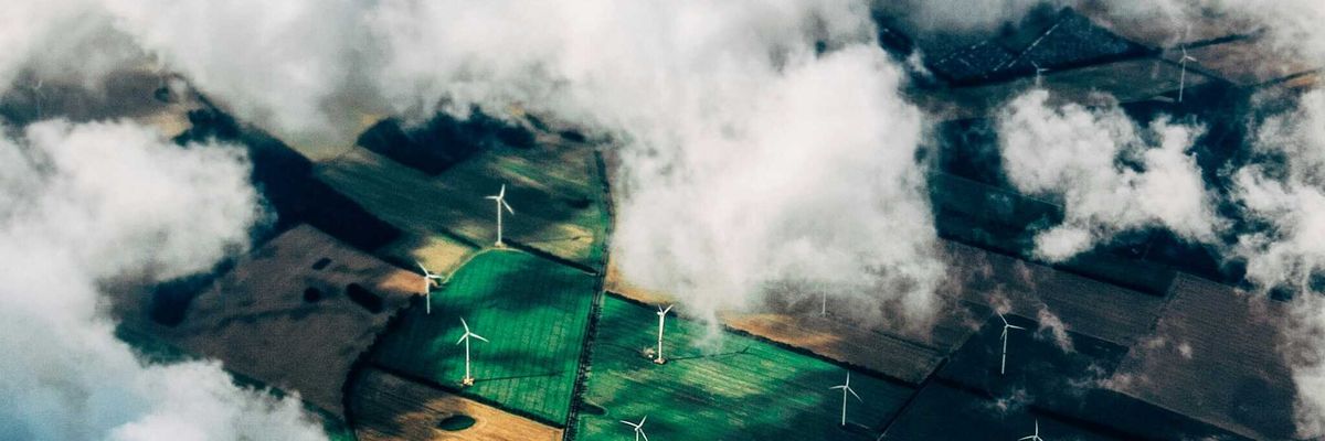aerial photo of wind turbines in fields with clouds drifting over.