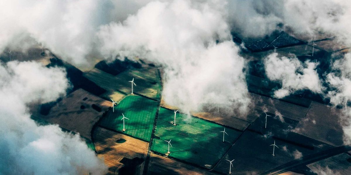 aerial photo of wind turbines in fields with clouds drifting over.