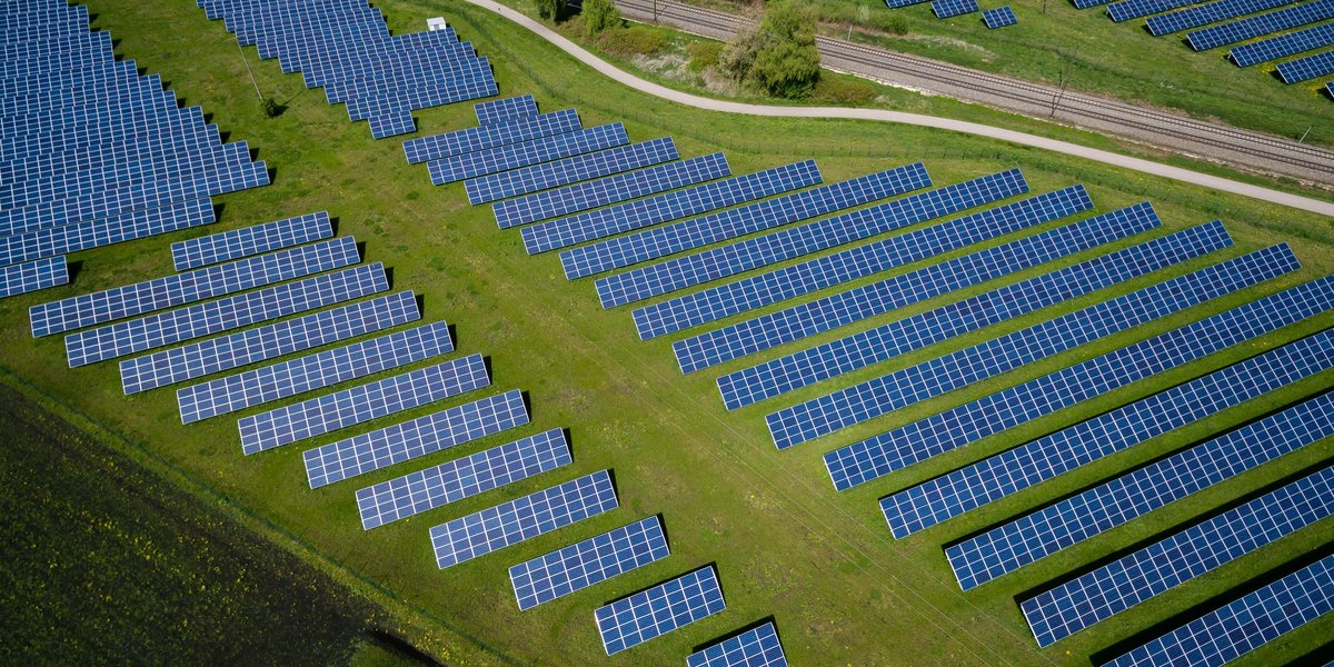 aerial photography of grass field with blue solar panels and a road.