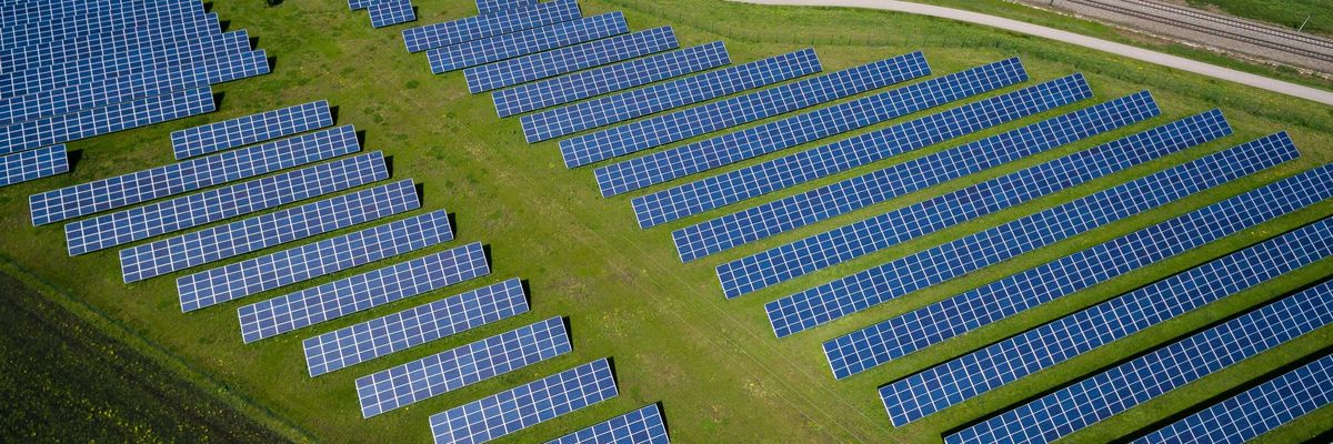 aerial photography of grass field with vast rows of solar panels.