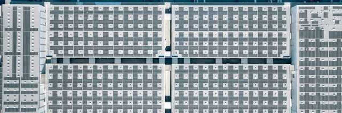 Aerial view of a city building with solar panels covering it and roads with cars on either side
