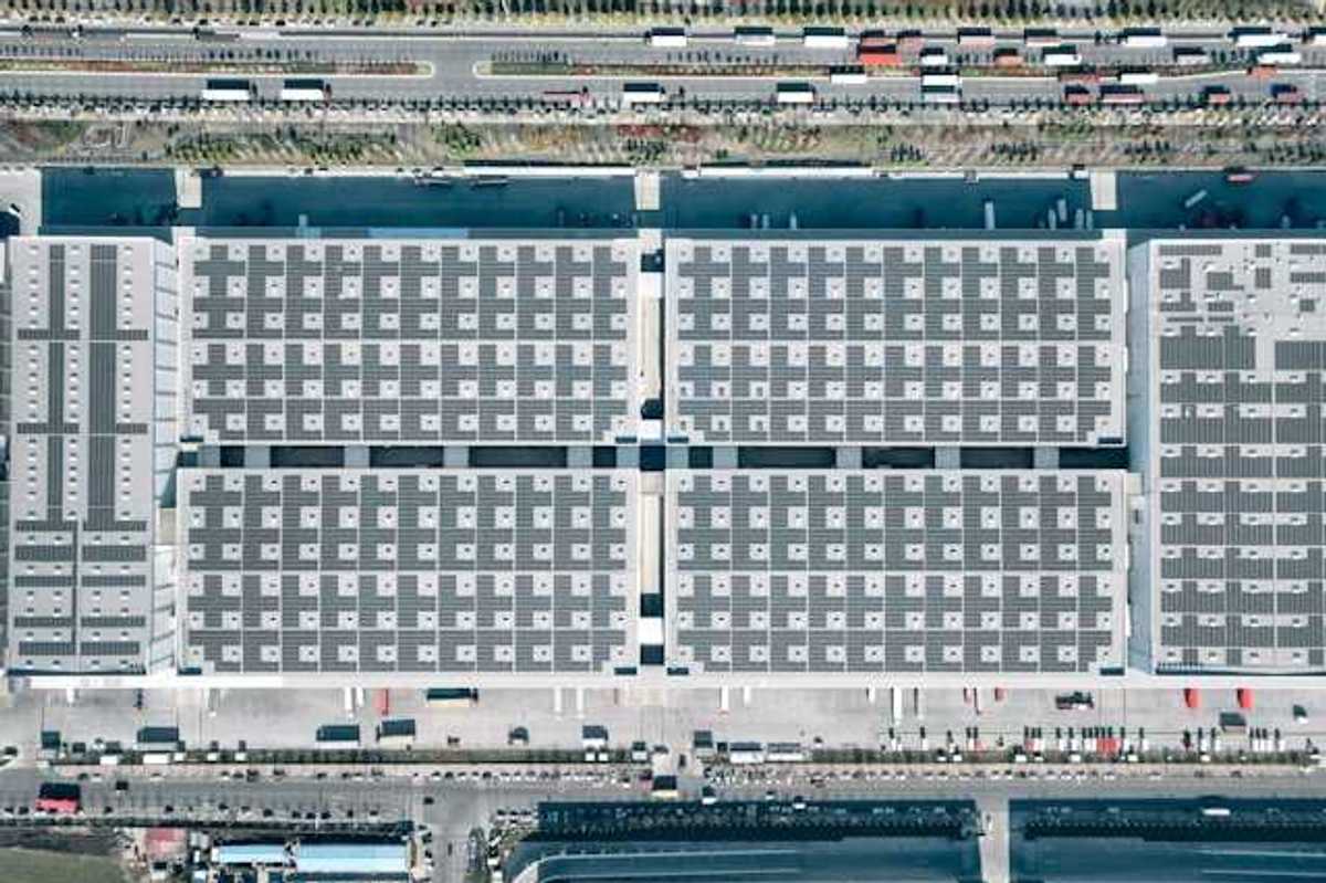 Aerial view of a city building with solar panels covering it and roads with cars on either side