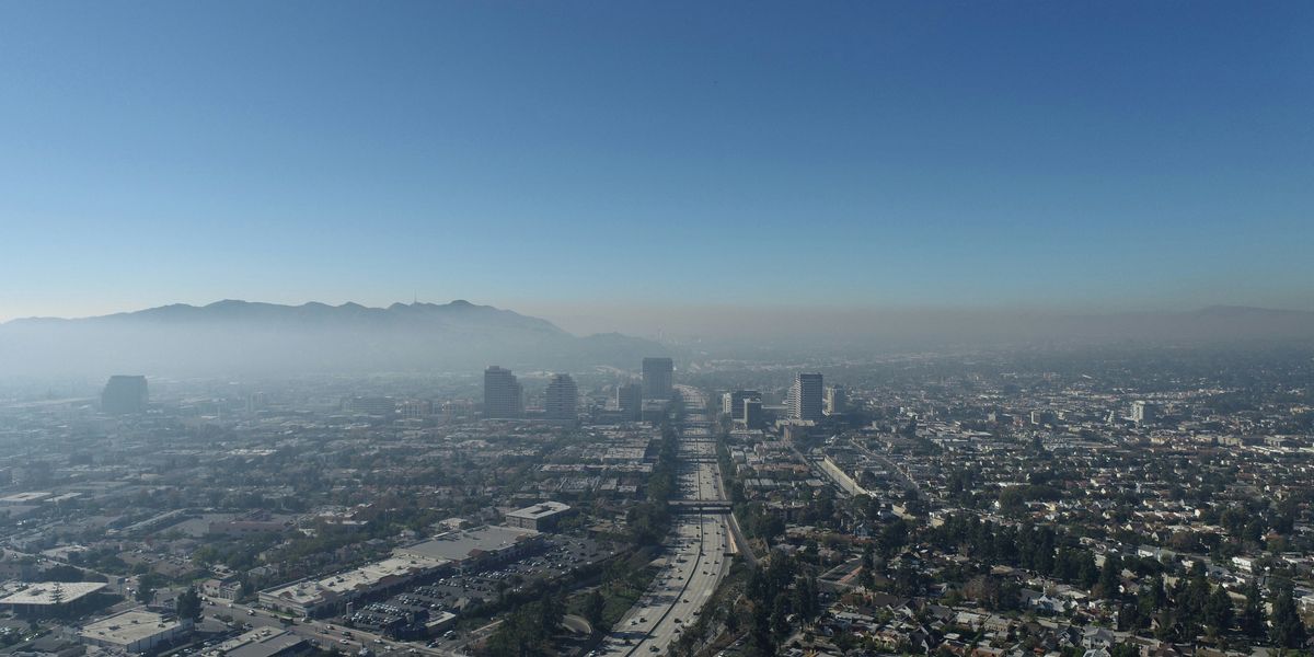 Aerial view of a city with smog covering the hills in the distance.