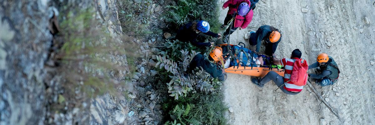 Aerial view of a group of search and rescue assisting a victim on an orange stretcher.