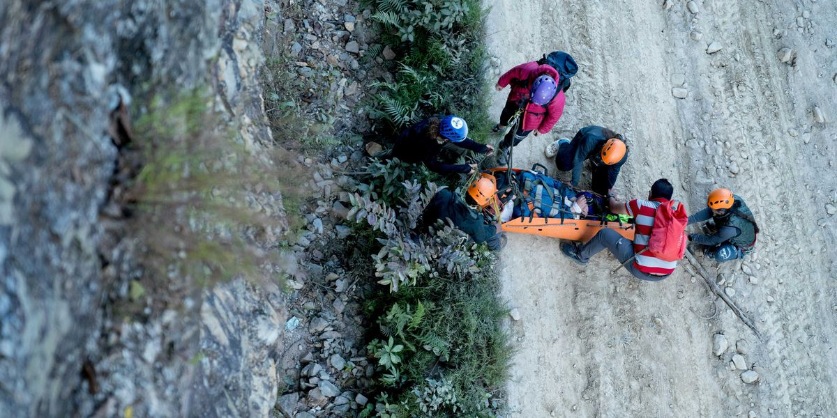 Aerial view of a group of search and rescue assisting a victim on an orange stretcher.