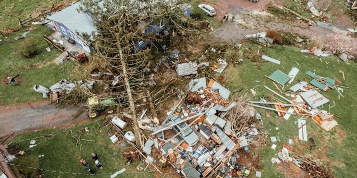 Aerial view of a home that has been damaged by a tornado or other natural disaster with debris scattered widely..