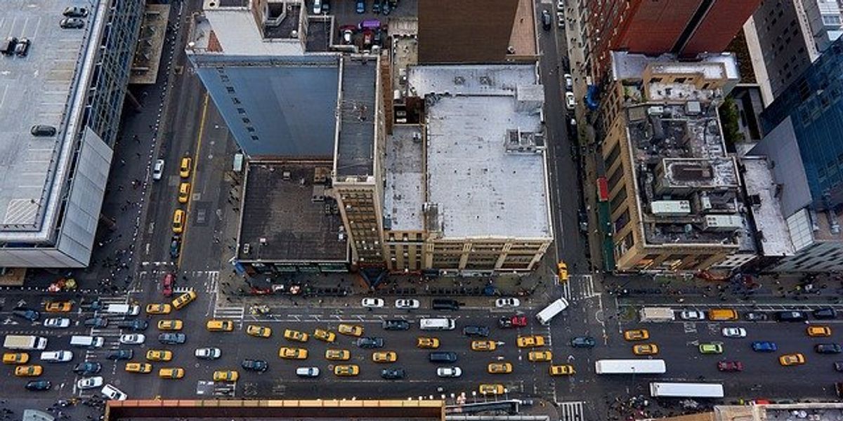 Aerial view of a New York street with buildings and streets filled with yellow taxis and other cars and trucks.