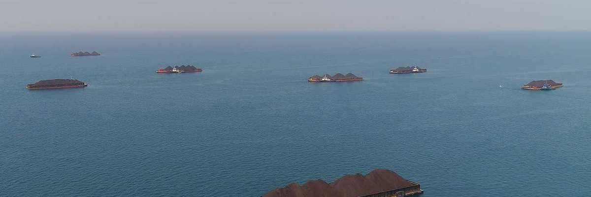 Aerial view of barges full of coal anchored at the sea near a coal-fired power station waiting be transported