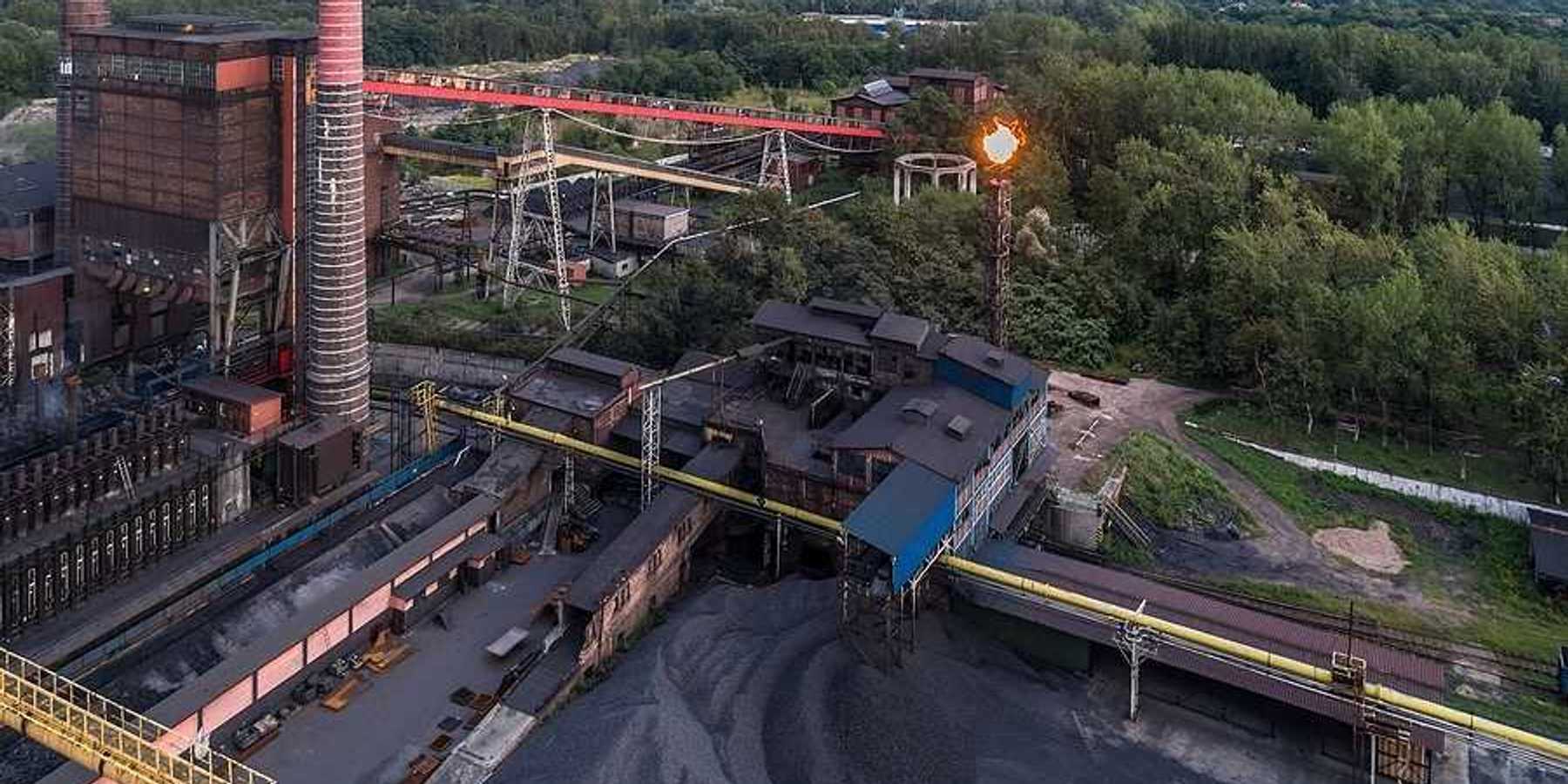 Aerial view on old working coking plant. Smokestacks, coal waste, flaring in progress.
