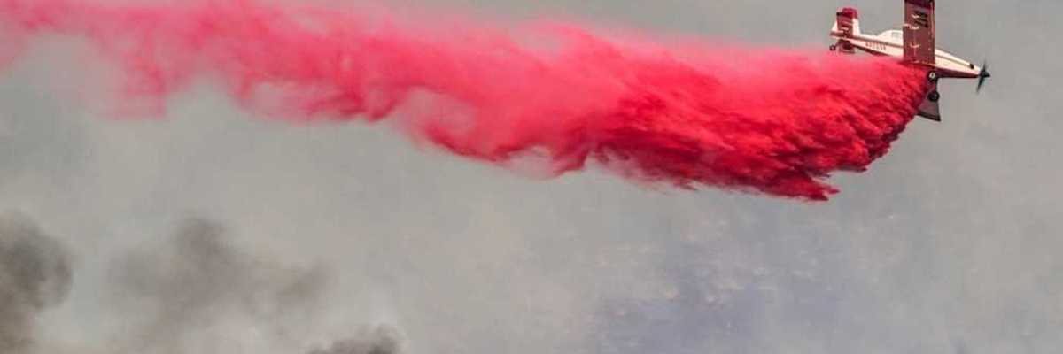 Airplane drops red fire retardant on a wildfire