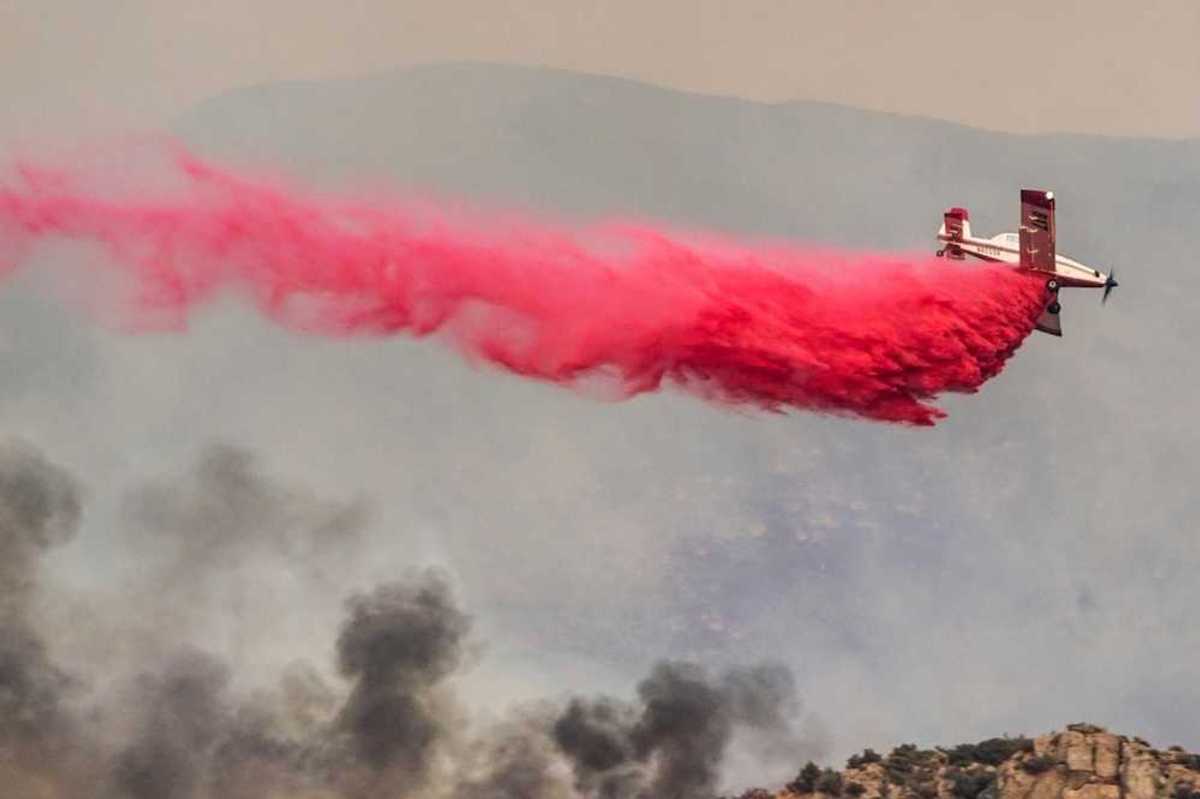 Airplane drops red fire retardant on a wildfire