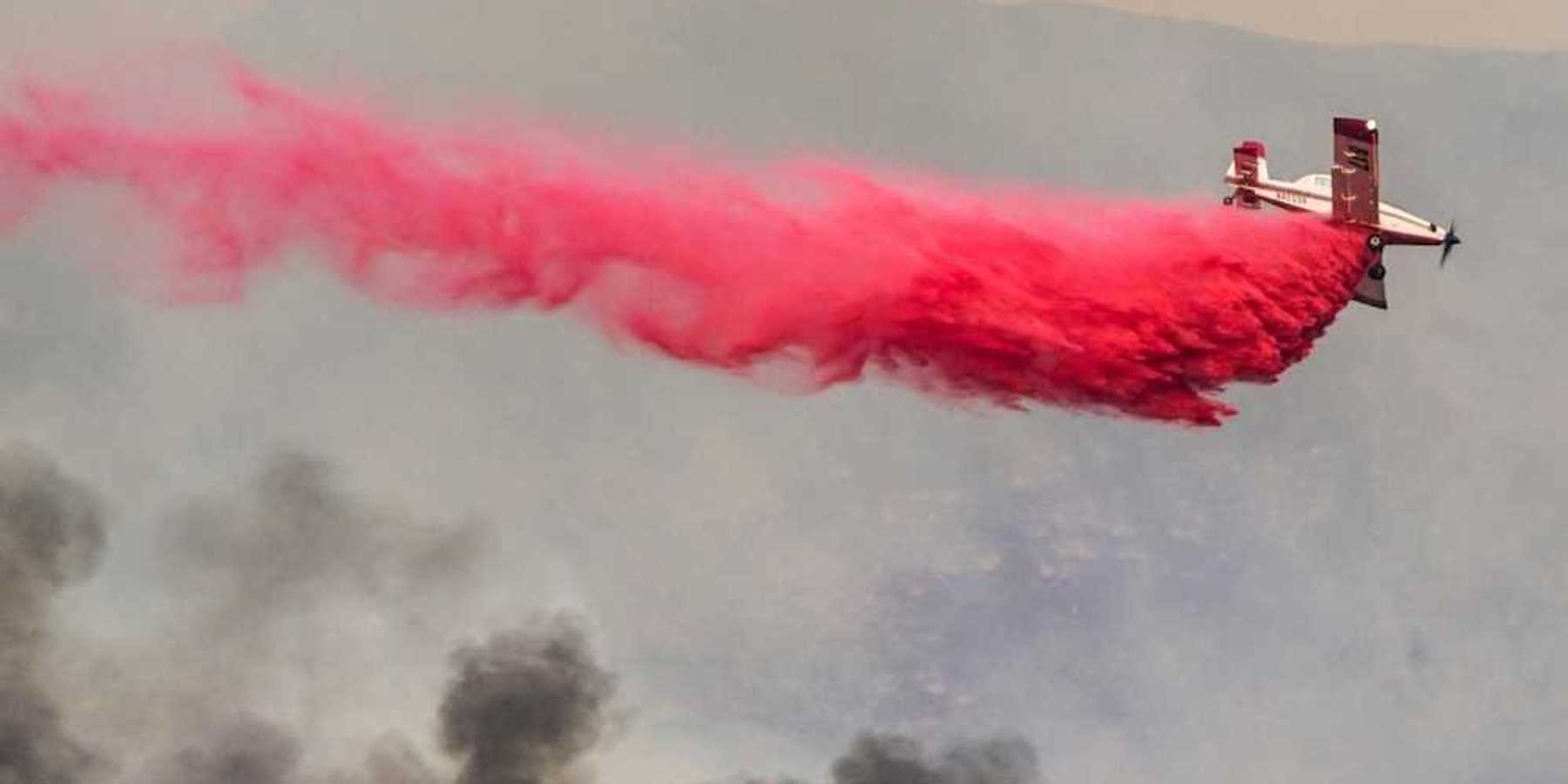 Airplane drops red fire retardant on a wildfire