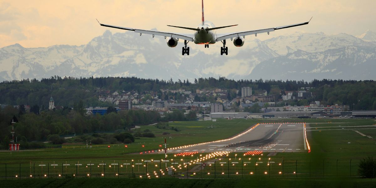 Airplane landing on a landing strip with snowy mountains in the background.