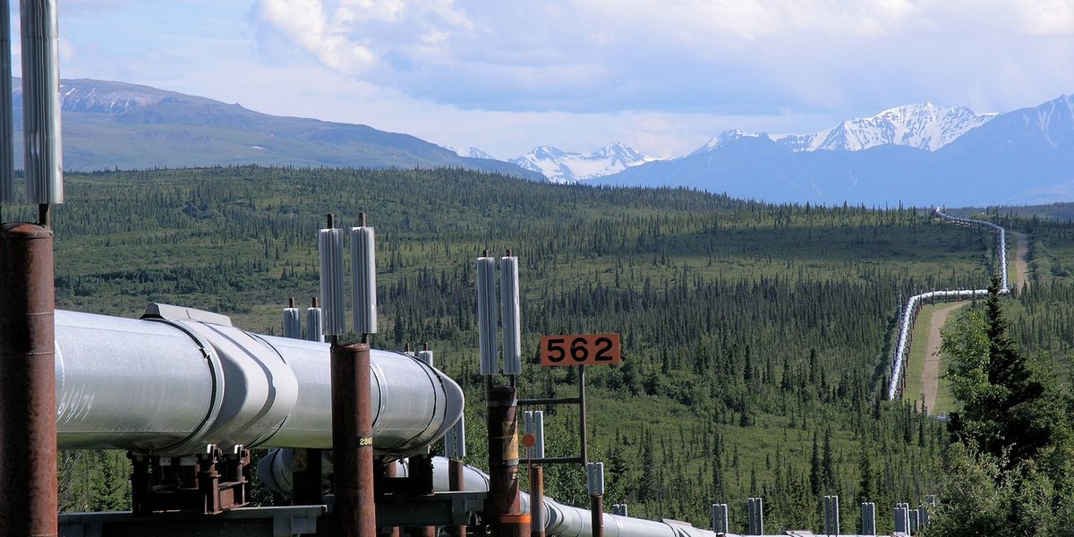Alaska oil & gas drilling pipeline with snowy mountains in background.