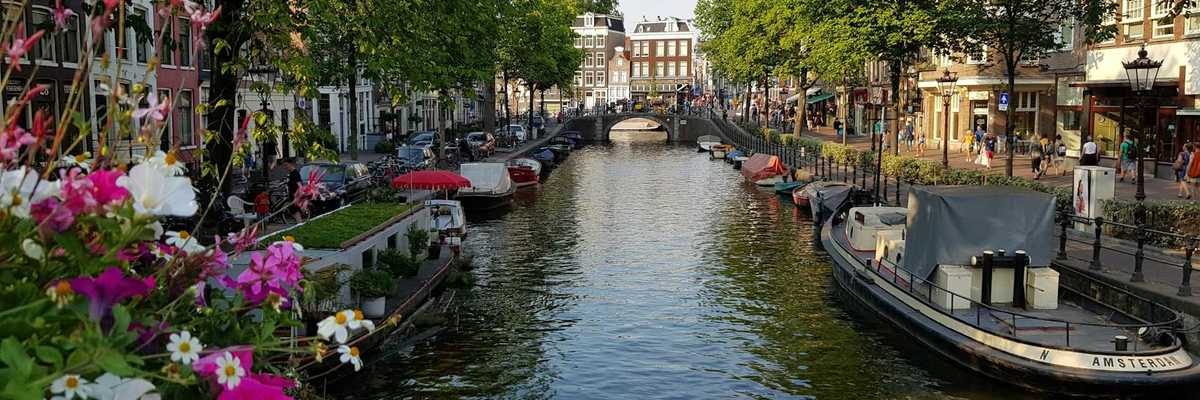Amsterdam street-lined canal with flowers and personal watercraft