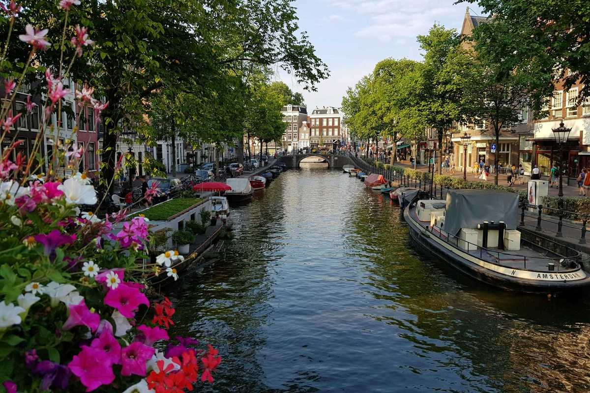 Amsterdam street-lined canal with flowers and personal watercraft