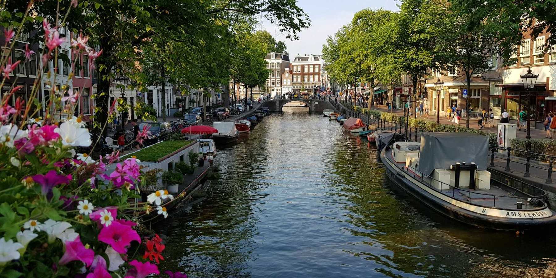 Amsterdam street-lined canal with flowers and personal watercraft
