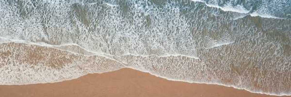 An aerial view of a beach with green water and waves
