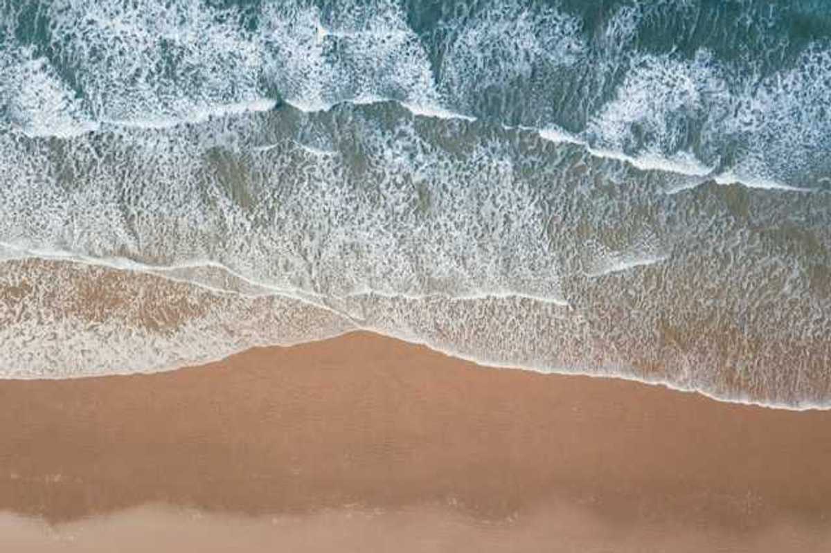 An aerial view of a beach with green water and waves
