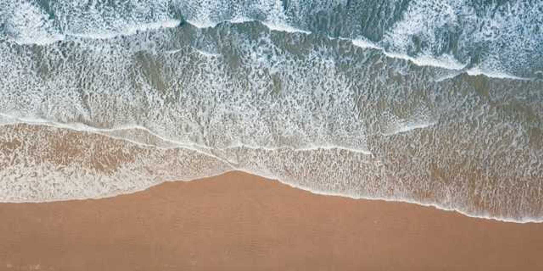 An aerial view of a beach with green water and waves