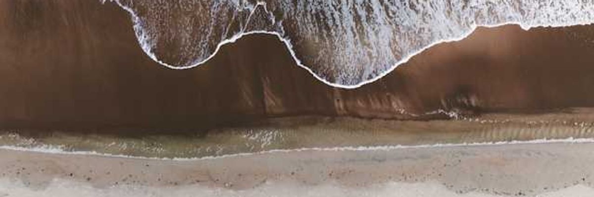 An aerial view of a beach with the waves encroaching