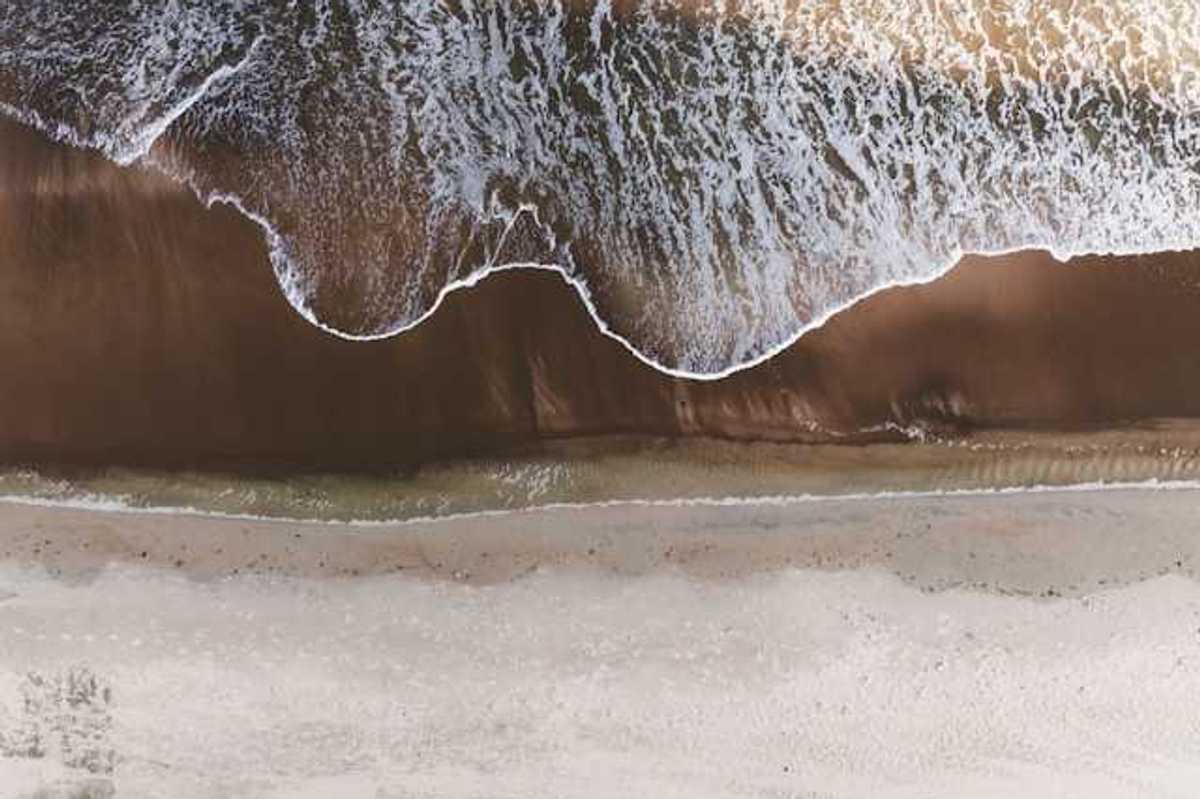 An aerial view of a beach with the waves encroaching